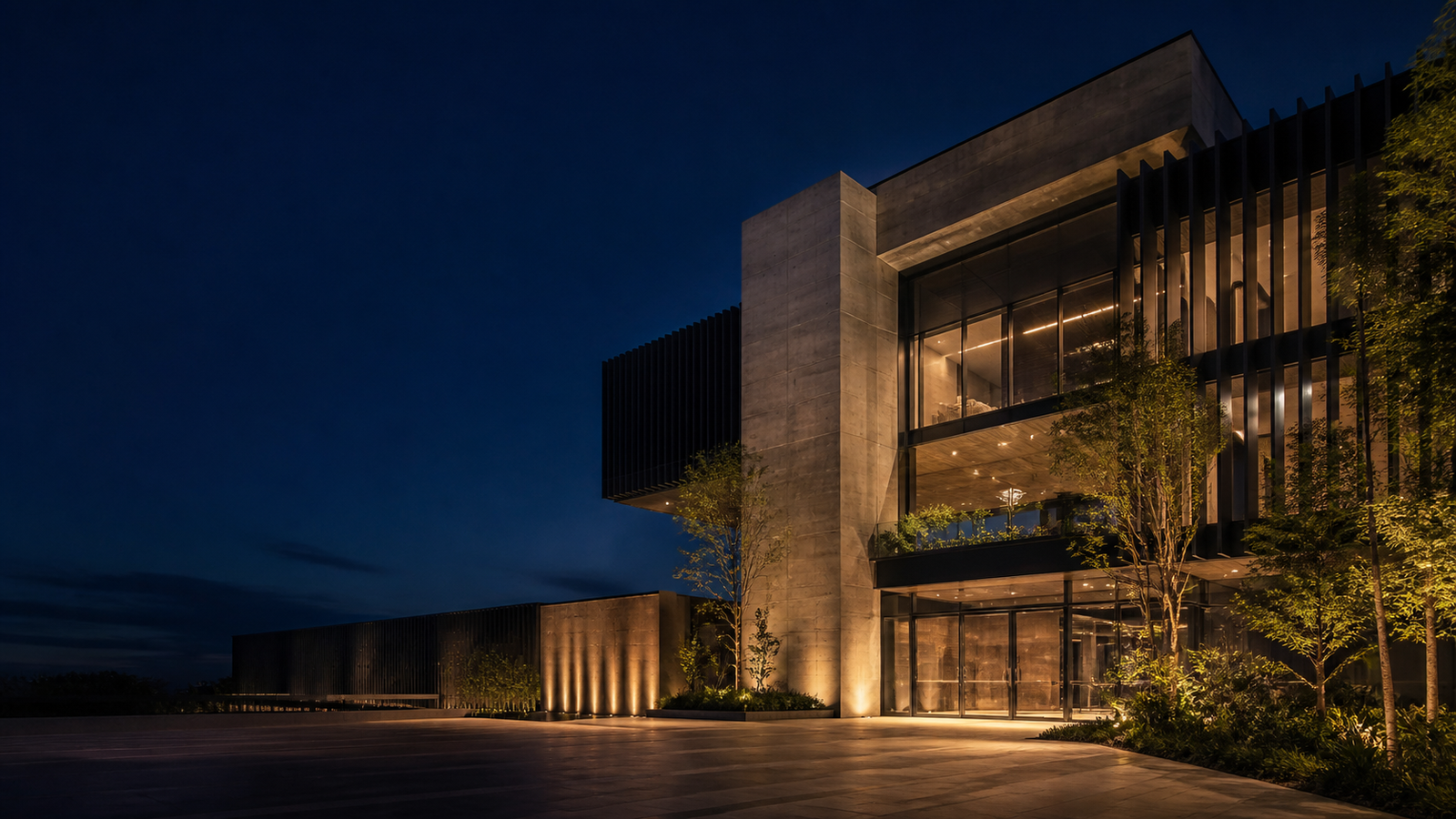 Edifício corporativo contemporâneo com estrutura de concreto, vidro e iluminação arquitetônica noturna